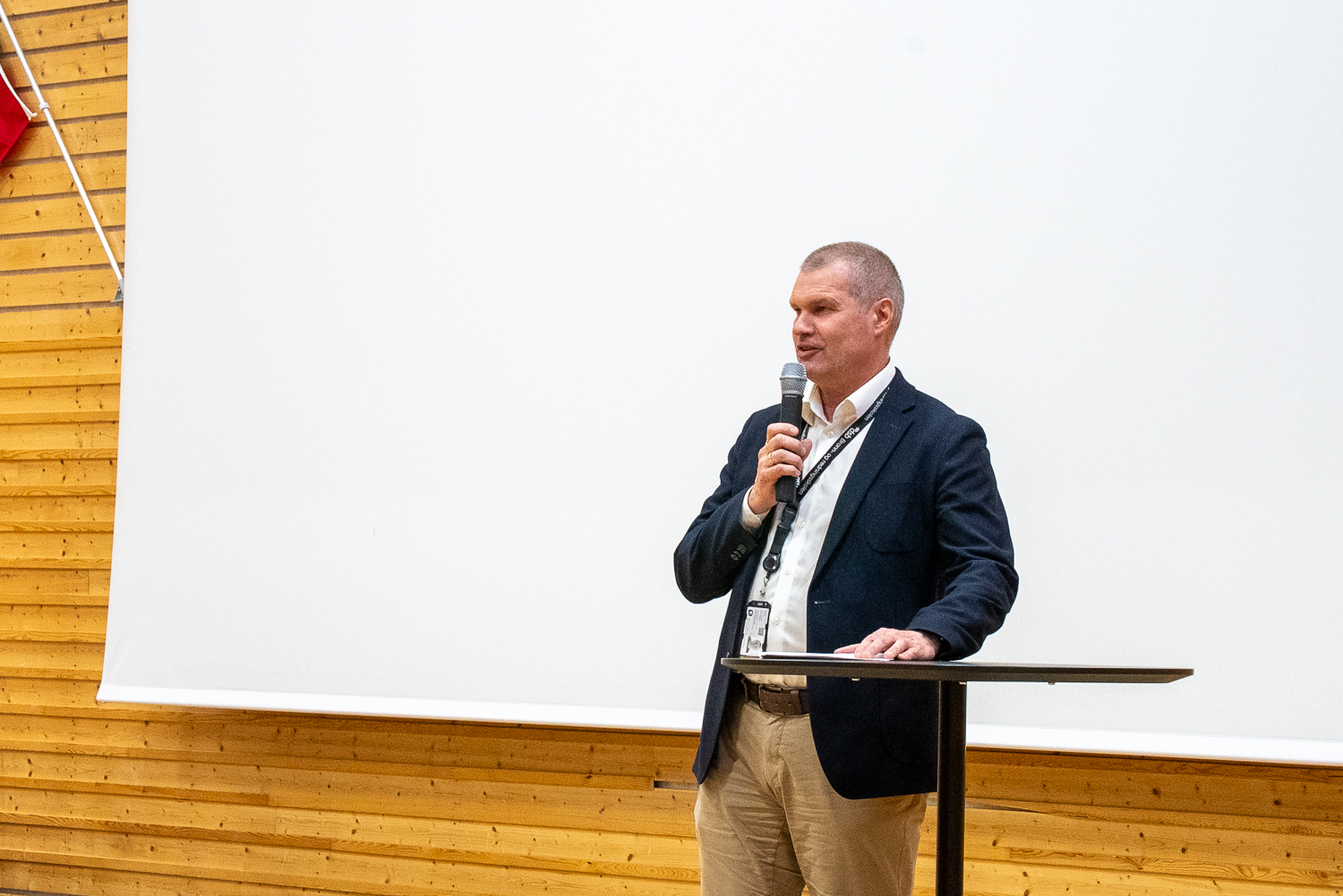 Mann i dress står foran et publikum og holder tale