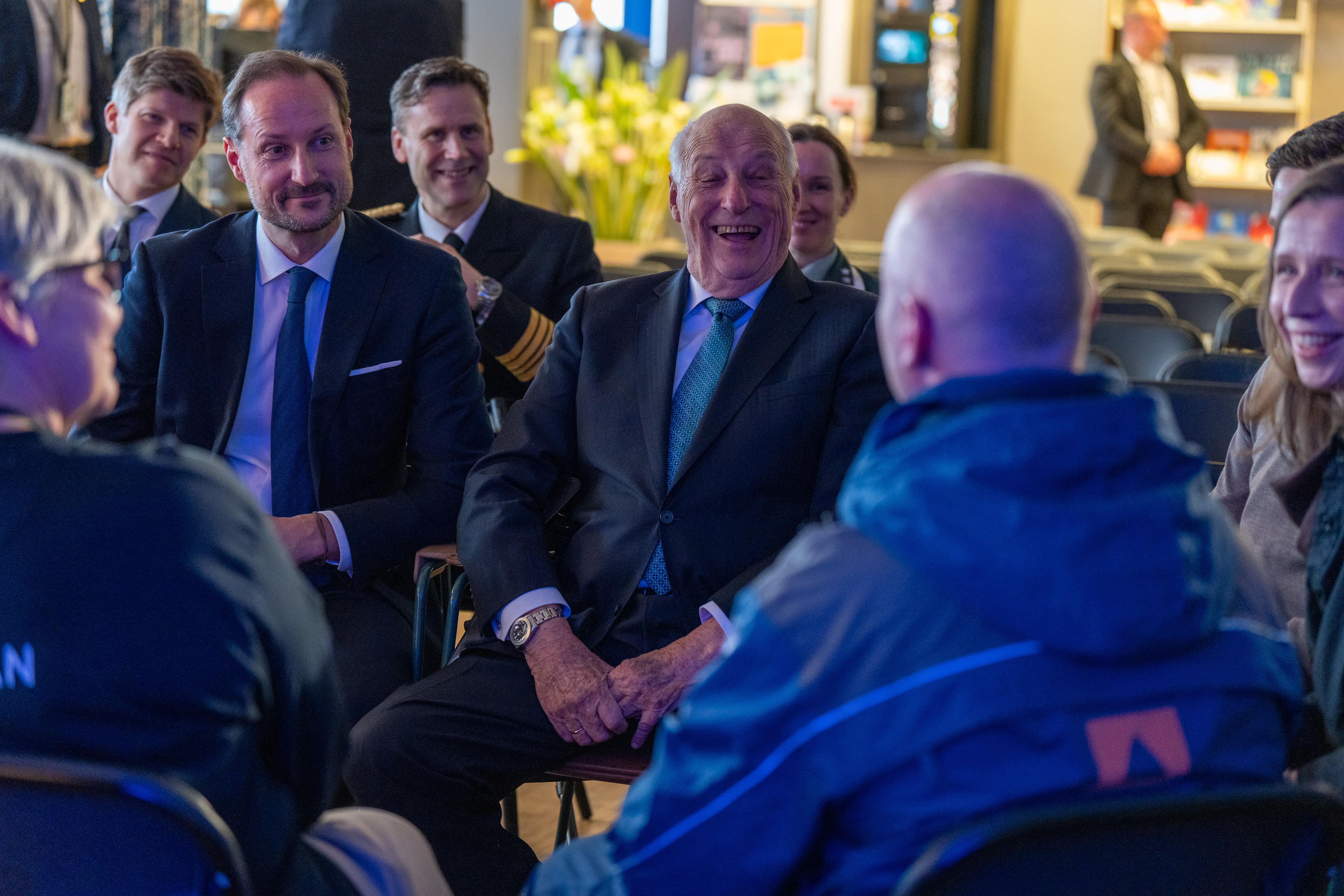 Bildet viser Kong Haakon og Kong Harald som ler. Vi ser også bakhodet til en mann fra Sivilforsvaret. 