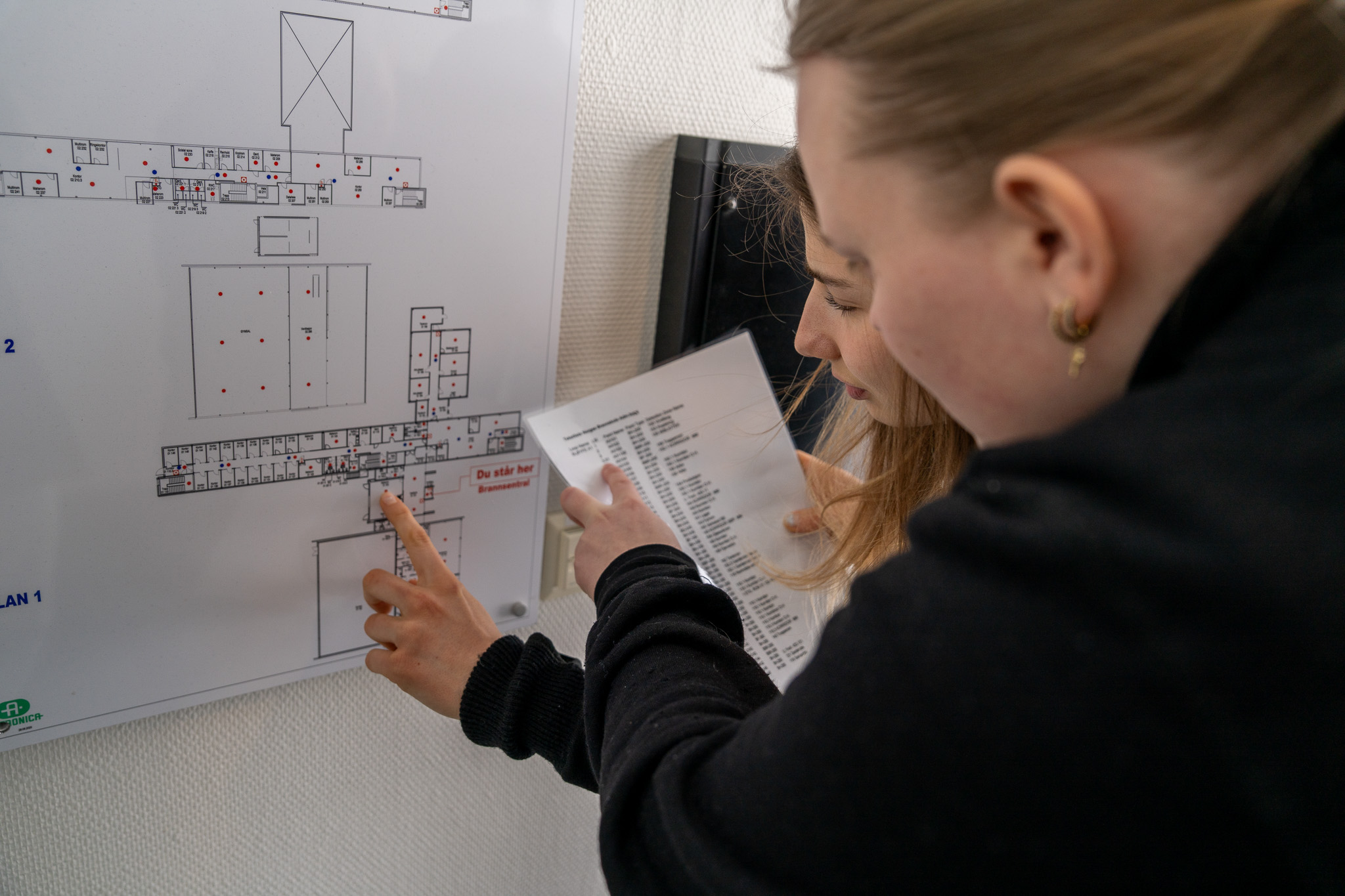 To kvinnelige studenter som sjekke kart over rømningsveier