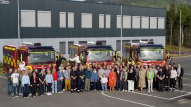 En stor gruppe mennesker står oppstilt og smiler mot kamera