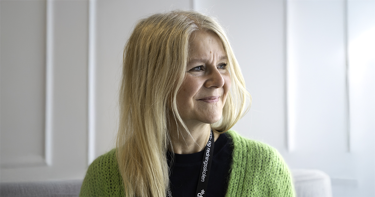 Kvinne med blondt hår og knallgrønn jakke ser til siden. Portrettfoto