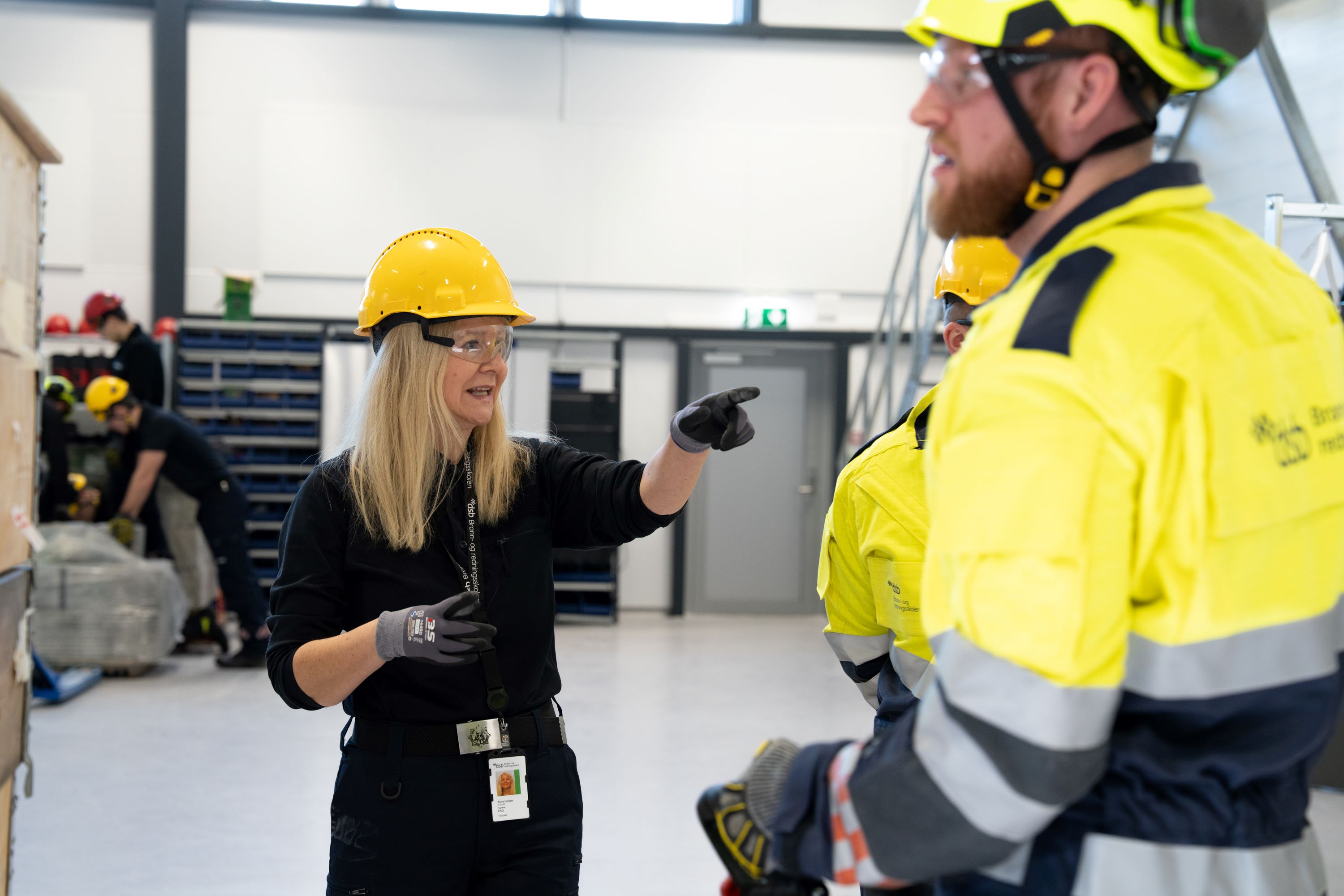 Kvinne i gul hjelm gir instrukser til studenter i trafikkdress