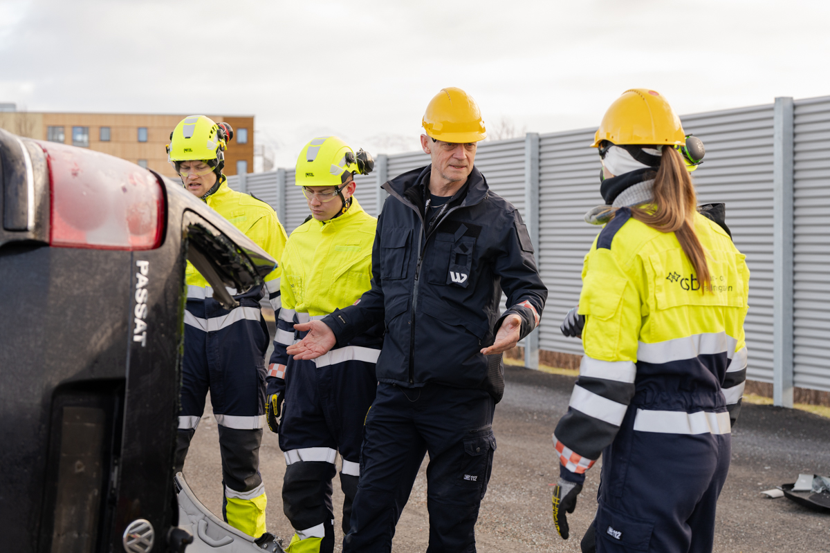 Undervisningssituasjon hvor deltakere har på seg trafikkdress og gul hjelm.