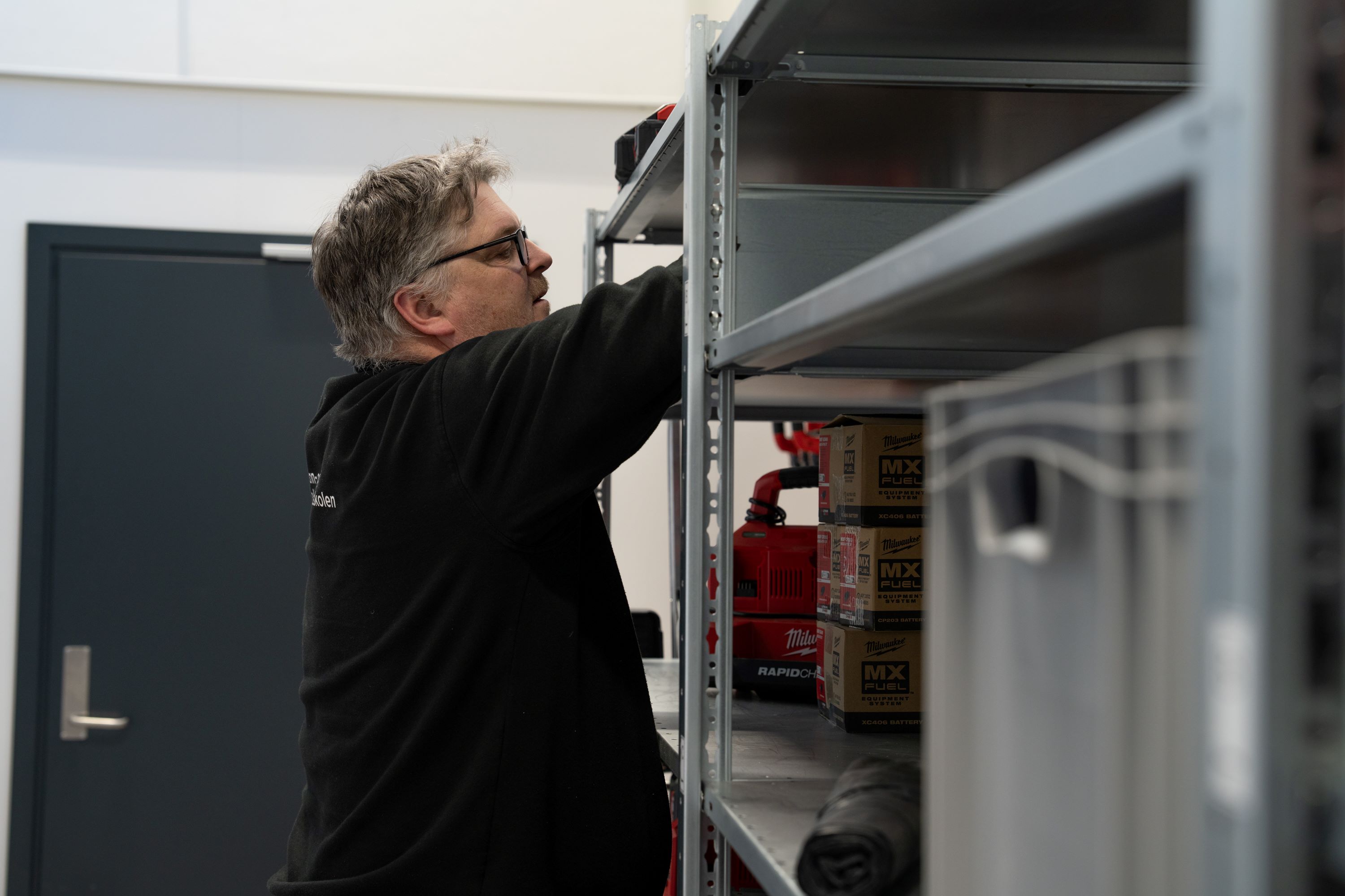 Mann organiserer i en hylle. Foto