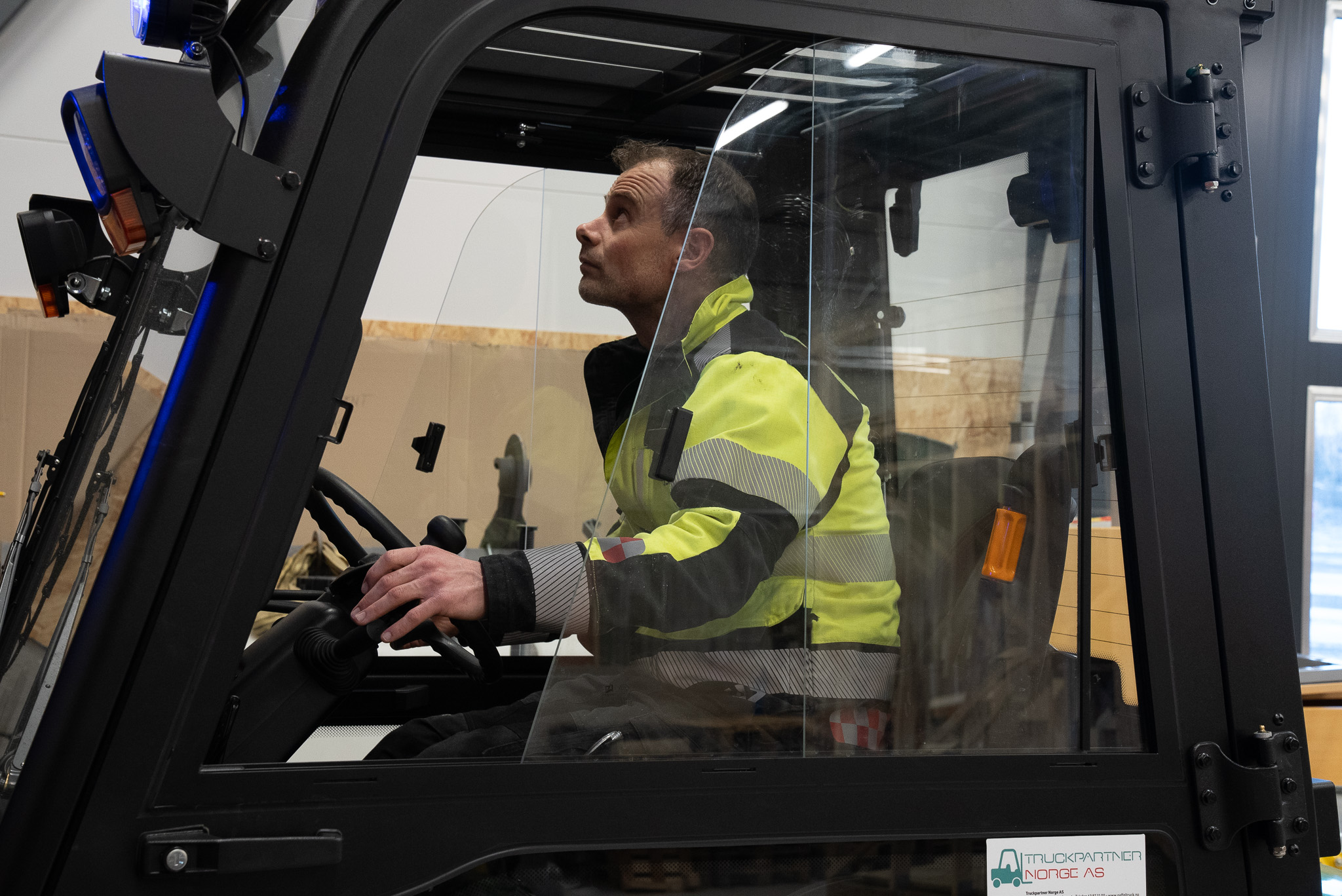 Nærbilde av fører i gaffeltruck sett fra siden.