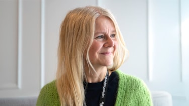 Kvinne med blondt hår og knallgrønn jakke ser til siden. Portrettfoto