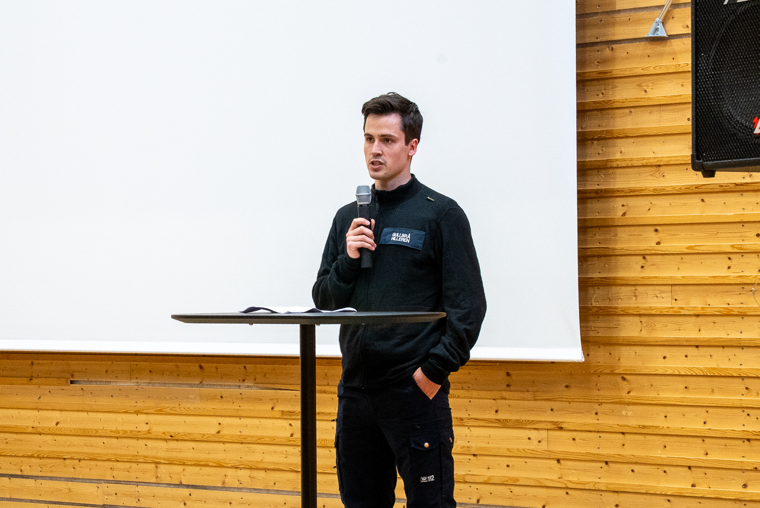 Mann i uniform står på en scene og taler til sine medstudenter.