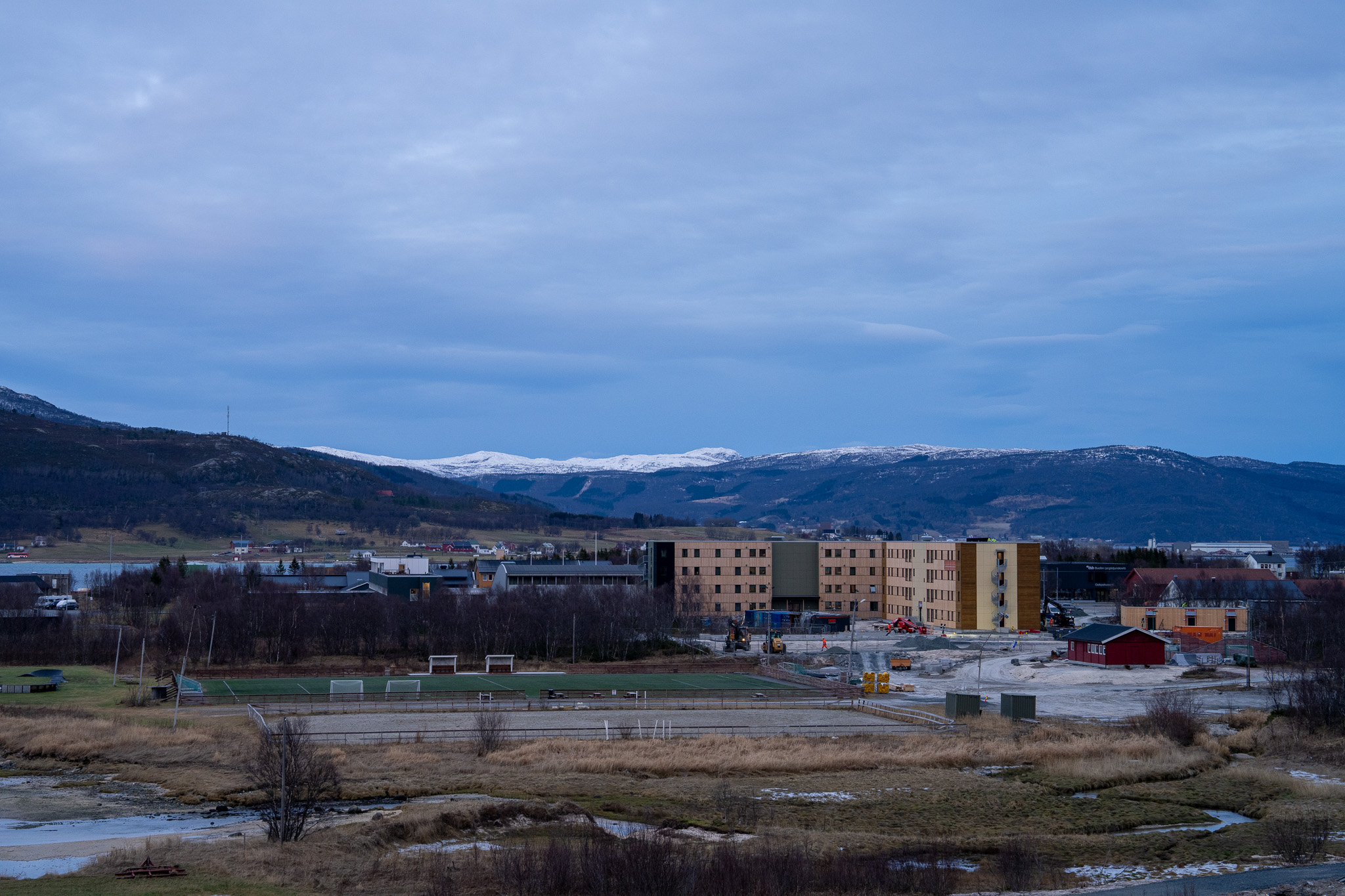 Et oversiktsbilde hvor man ser studentboliger i horisonten og fjell bak.