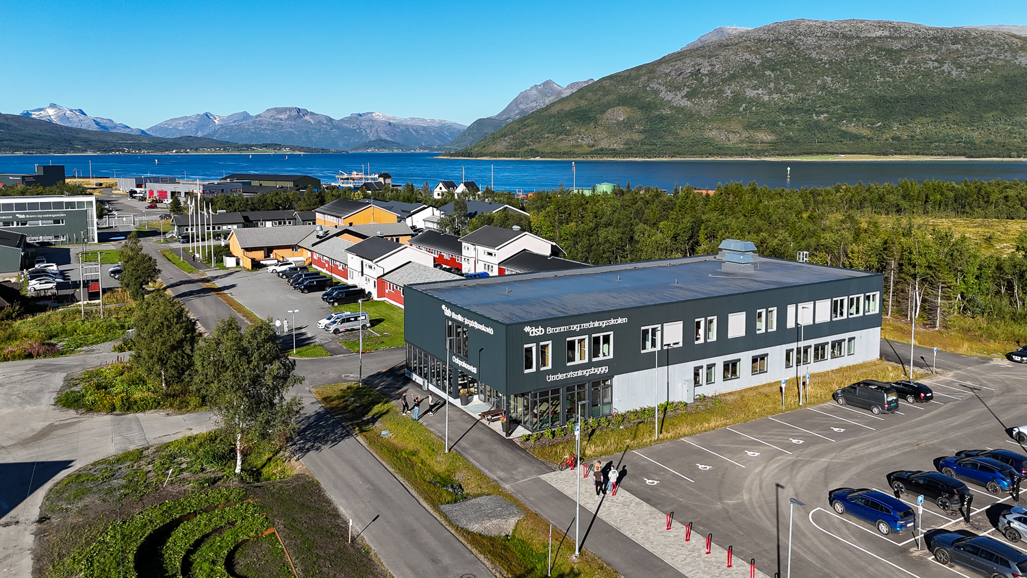 Dronebilde av et undervisningsbygg på campus. Fjell og fjord i bakgrunnen