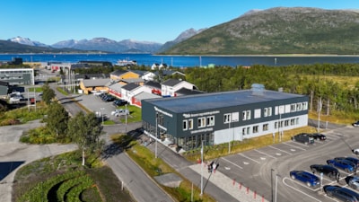 Dronebilde av et undervisningsbygg på campus. Fjell og fjord i bakgrunnen