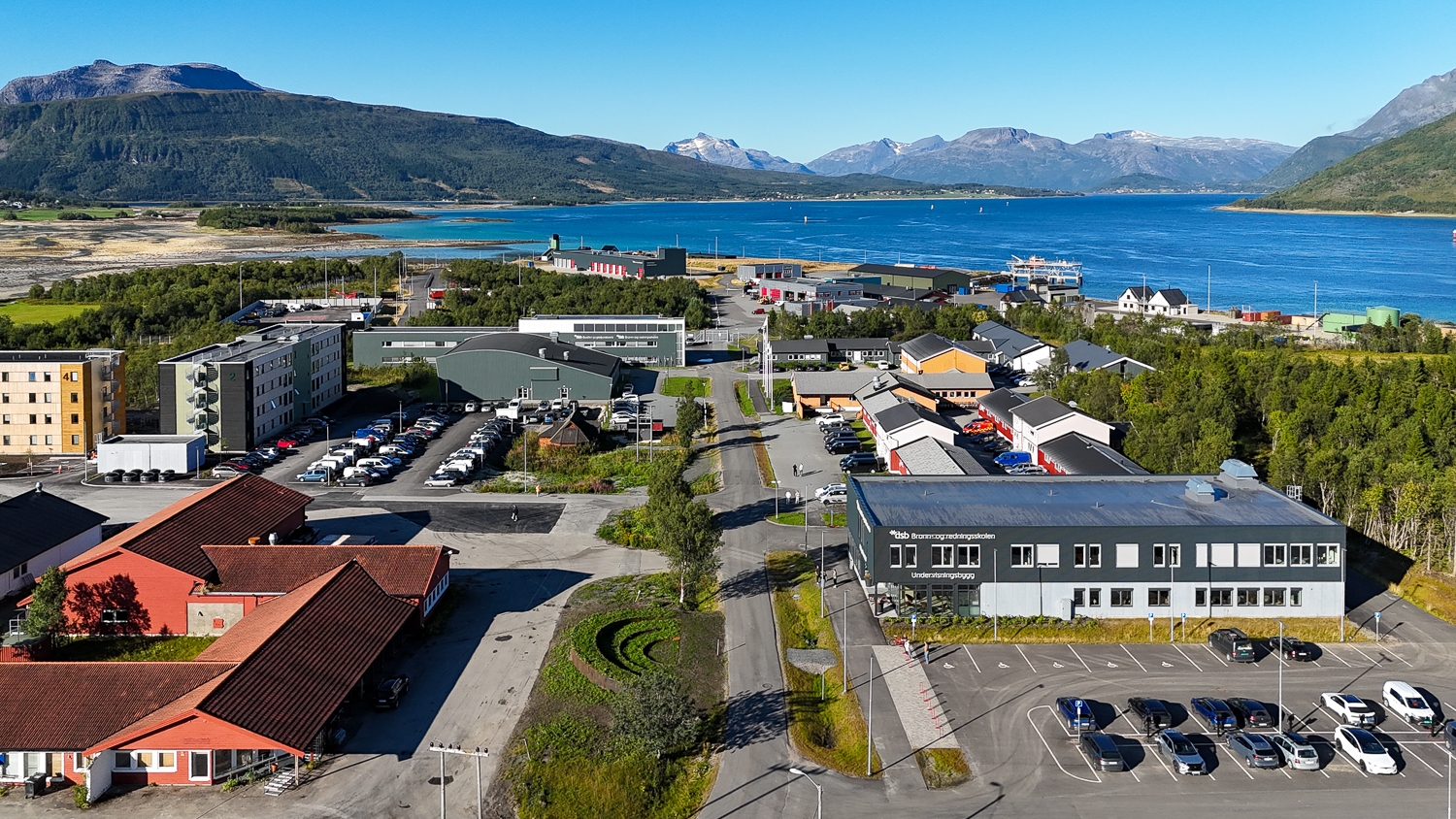 Oversiktsbilde over et campus med flere bygg. Fjell og fjord i bakgrunnen. 