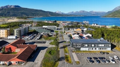 Oversiktsbilde over et campus med flere bygg. Fjell og fjord i bakgrunnen.