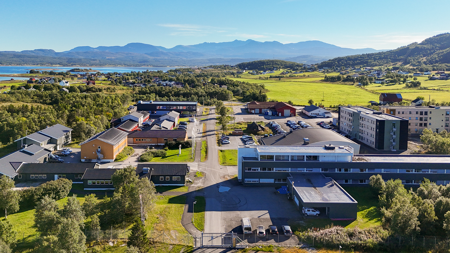 Oversiktsbilde over et campus med mye grønn natur og havet i bakgrunnen