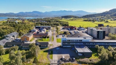 Oversiktsbilde over et campus med mye grønn natur og havet i bakgrunnen