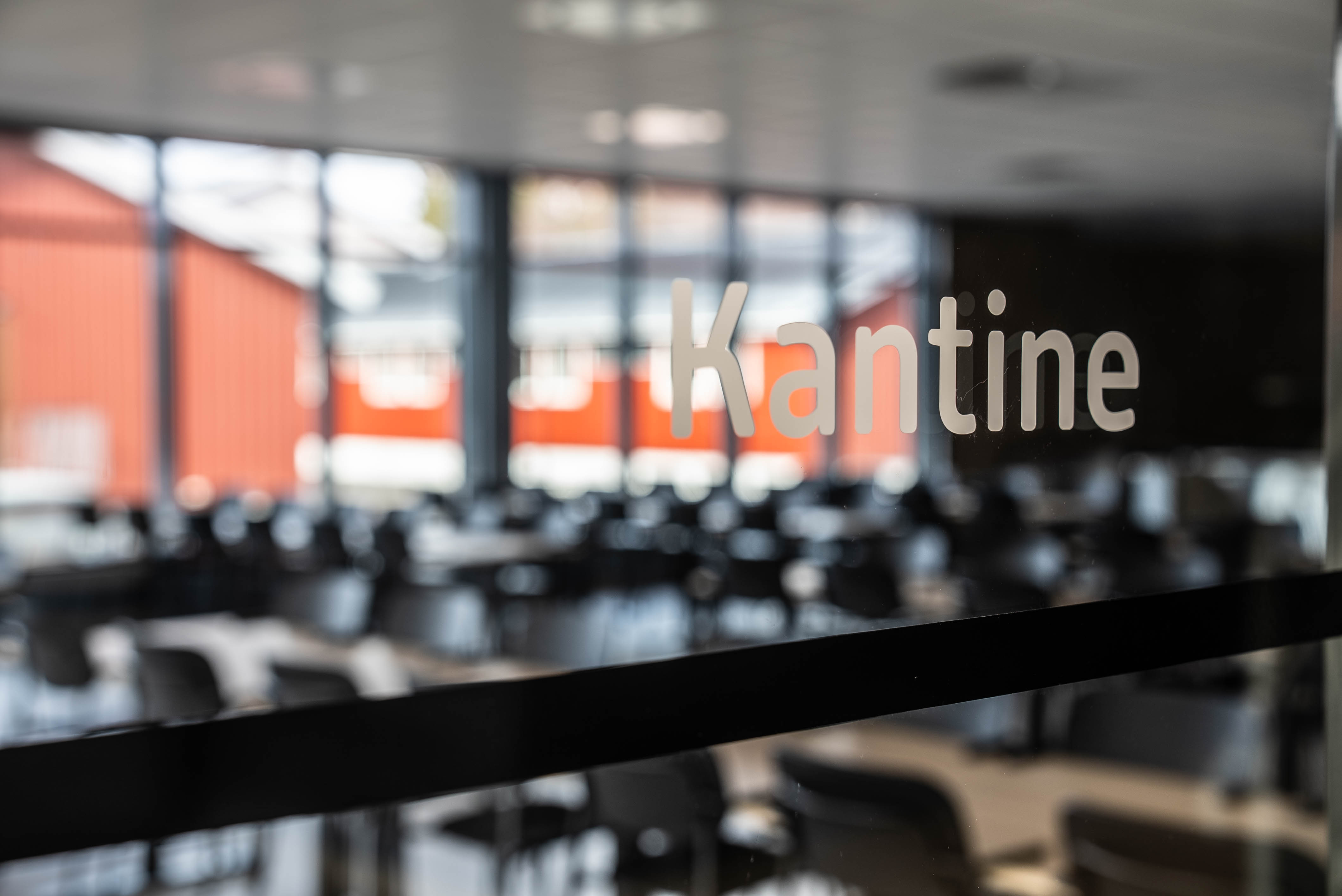 Bilde tatt gjennom et vindu med teksten "kantine". 