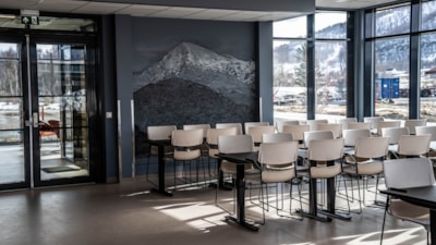 Et tomt bord og mange stoler. I bakgrunnen er et fjell malt på en vegg. Foto