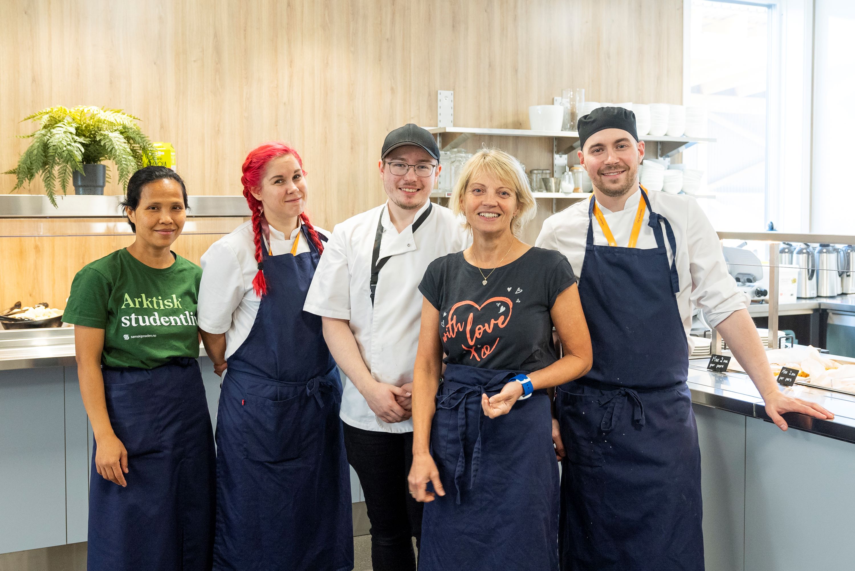Fem mennesker i kjøkkenuniform smiler mot kamera