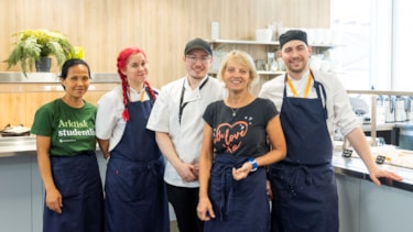 Fem mennesker i kjøkkenuniform smiler mot kamera