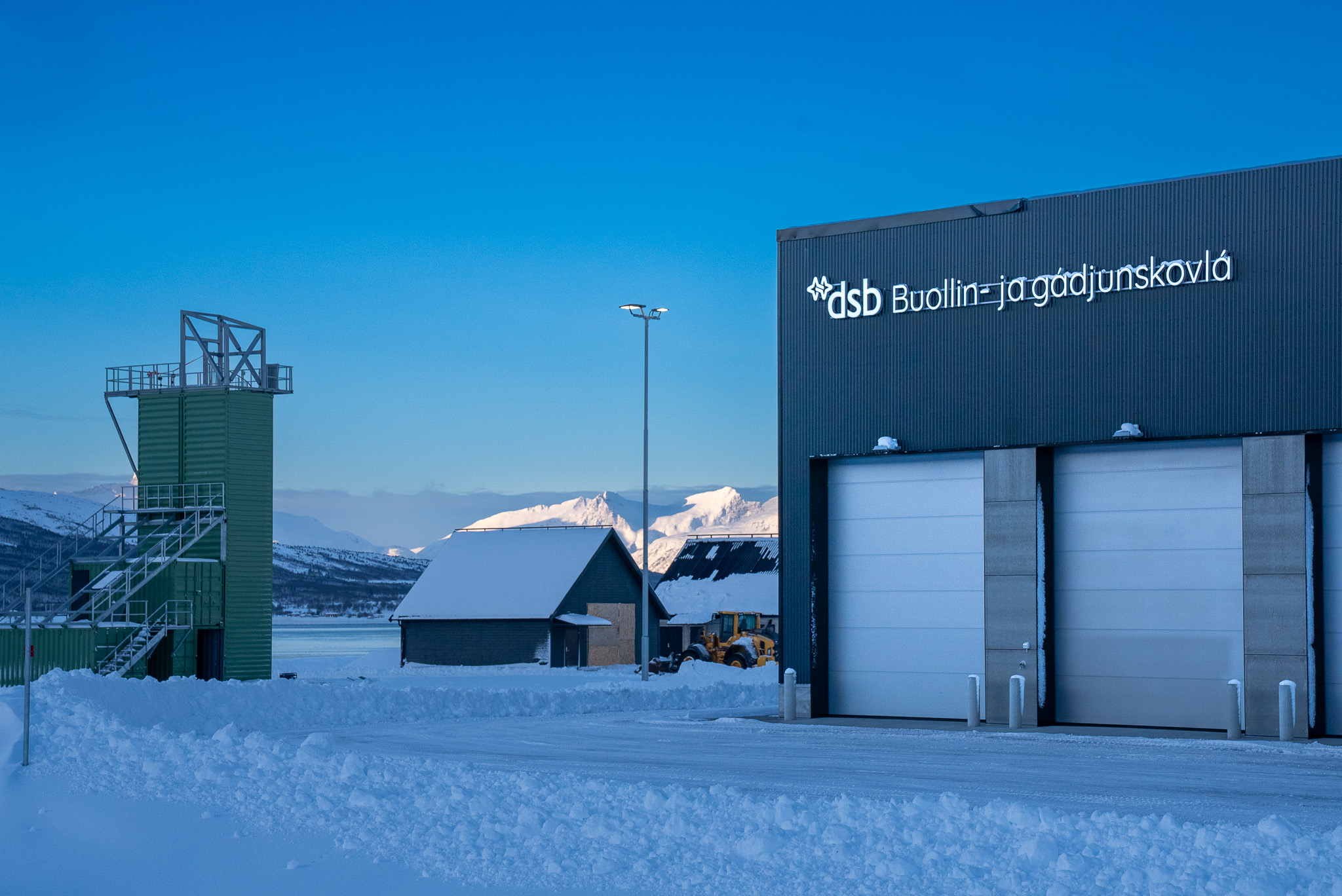 En brannstasjon, et lite hus og et vakttårn. Blå himmel bak.