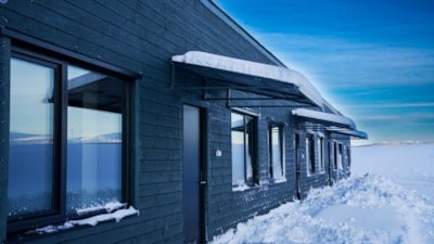 Fire hus i rekke, blå himmel bak. Snø på bakken foran.