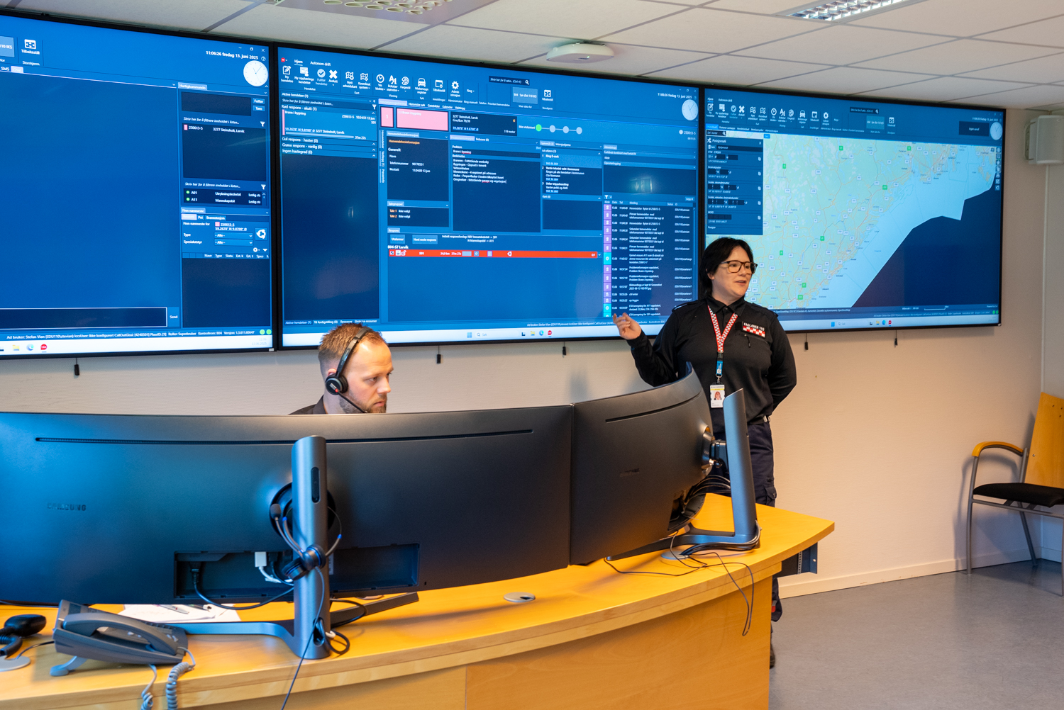 En mann sitter bak to skjermer. En dame står foran tre skjermer som viser kart og data