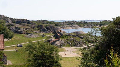 Utsikt over fjord, grønt gress, berg og en sandvolleyballbane