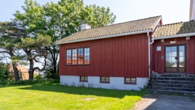 Et lite rødt bygg med et stort tre ved siden av seg