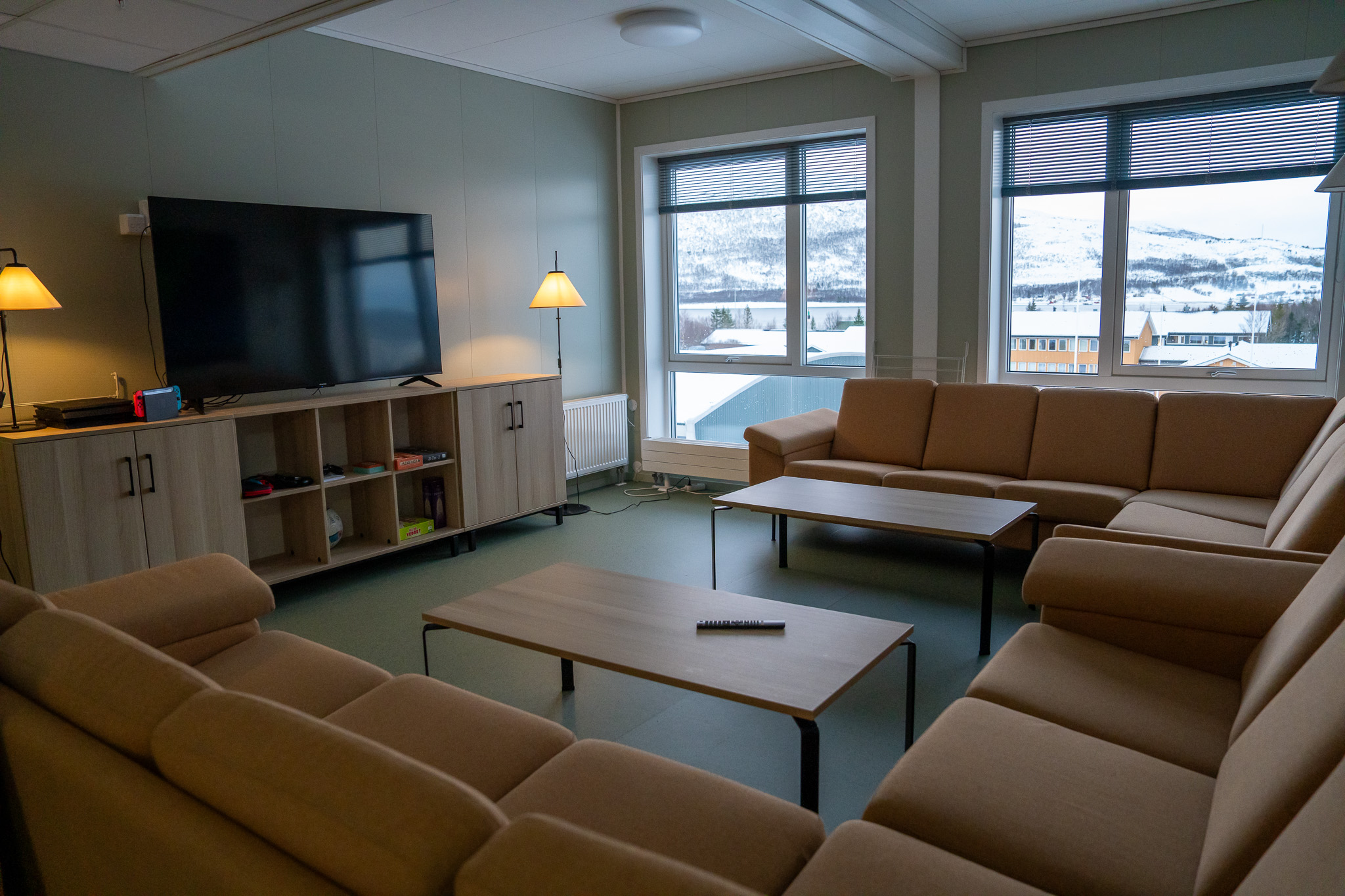 En stor oransje sofa og to bord rettet mot en tv som står på en tv-seksjon