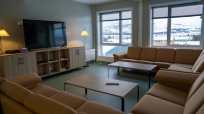 En stor oransje sofa og to bord rettet mot en tv som står på en tv-seksjon
