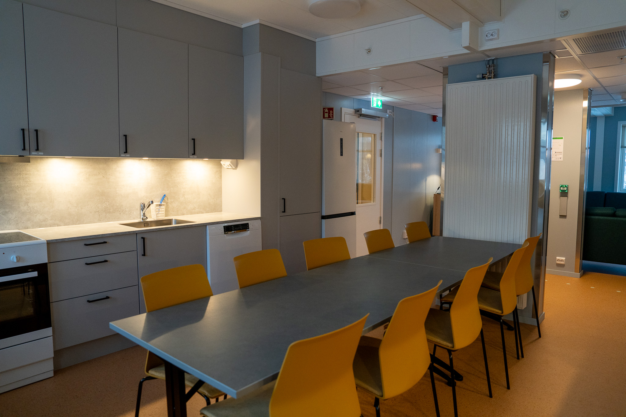 Et spisebord med ti stoler står på et kjøkken