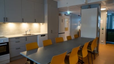 Et spisebord med ti stoler står på et kjøkken