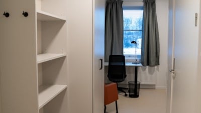 En stor hylle til venstre. Stol, pult og vindu rett fram.