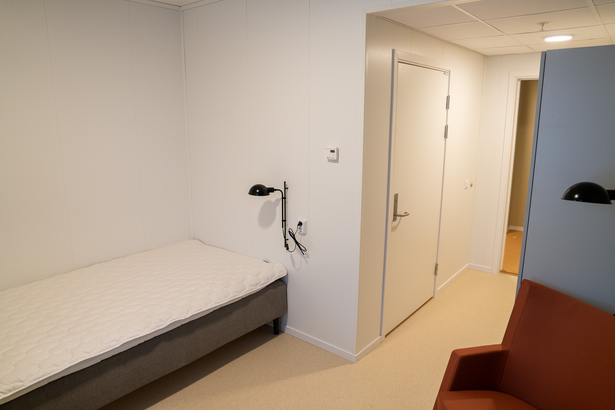 En seng til venstre, en stol til høyre. Dør til bad rett fram