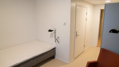 En seng til venstre, en stol til høyre. Dør til bad rett fram