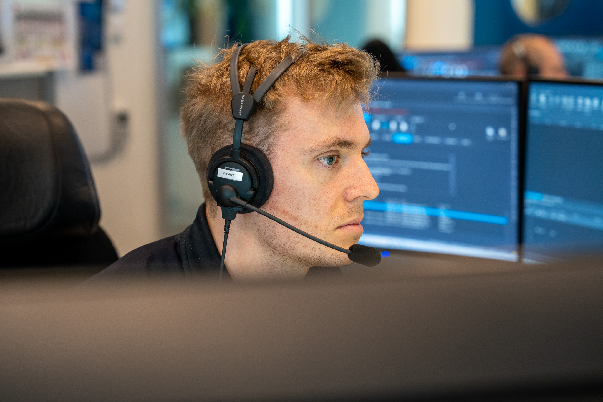 En mannlig student sitter med headset foran skjermer på 110-sentral