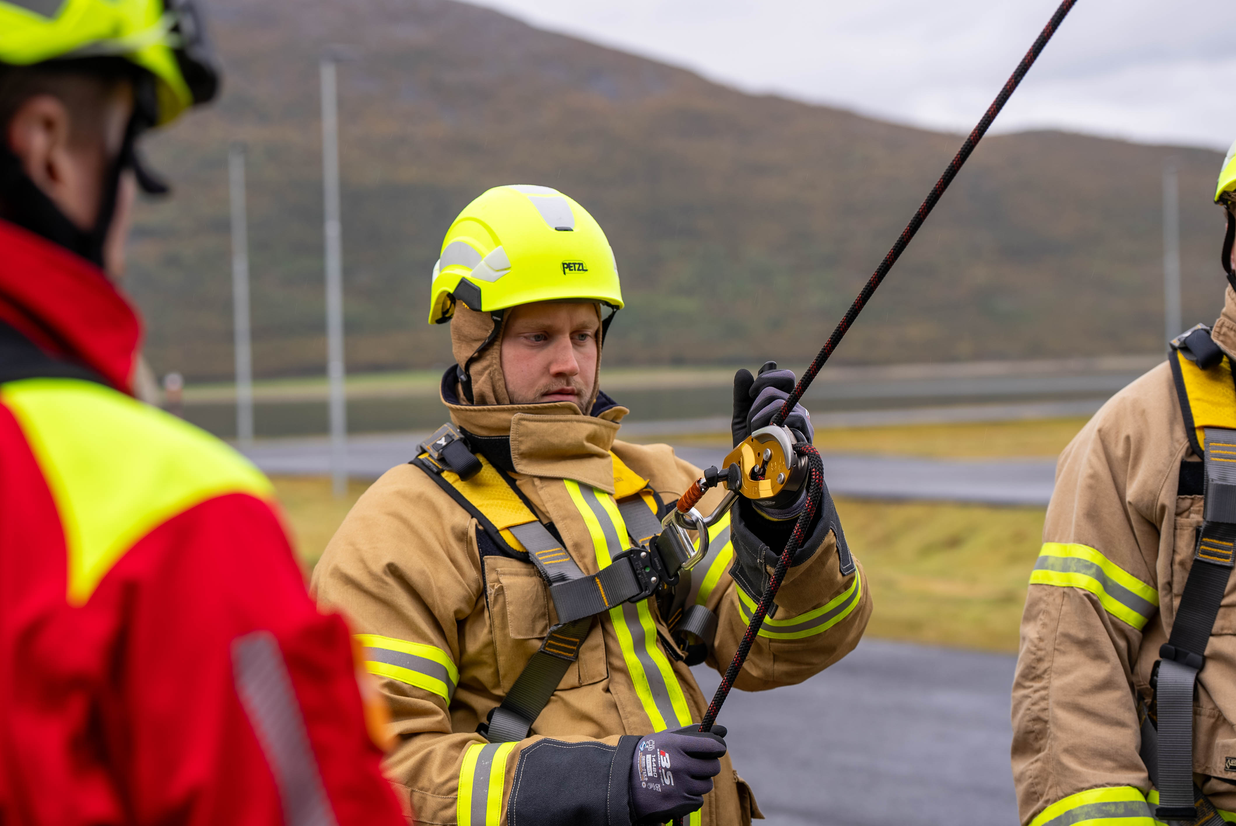 En brannkonstabel i uniform med et tau festet rundt seg