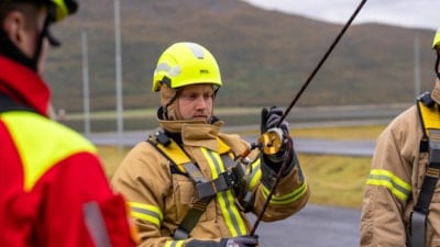 En brannkonstabel i uniform med et tau festet rundt seg