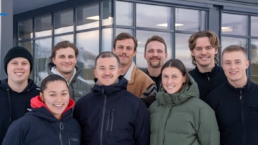 Ni blide studenter ser rett inn i kamera.