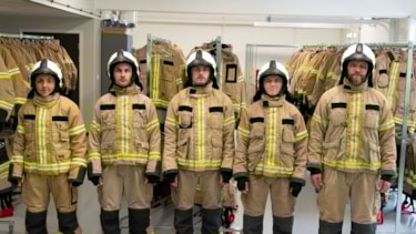 Fem studenter ikledd røykdykkerbekledning. De står oppstilt på rekke og ser mot kamera. Foto