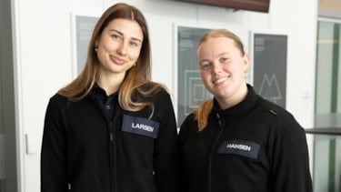 To uniformerte kvinnelige studenter smiler mot kamera. Foto
