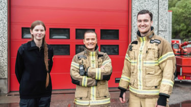 En brannforebygger og to brannkonstabler smiler mot kamera