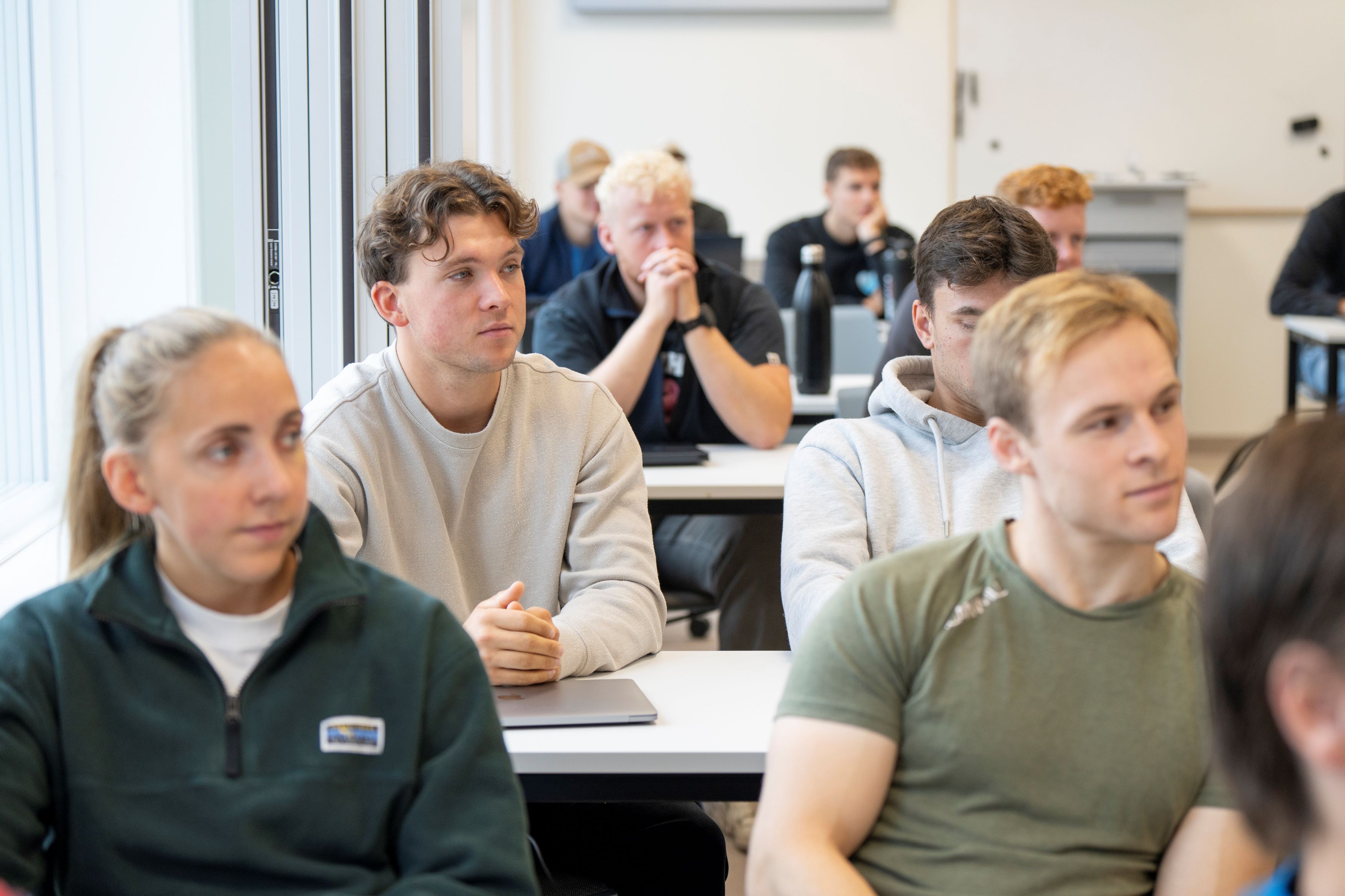 Studenter sitter ved pulter i undervisning