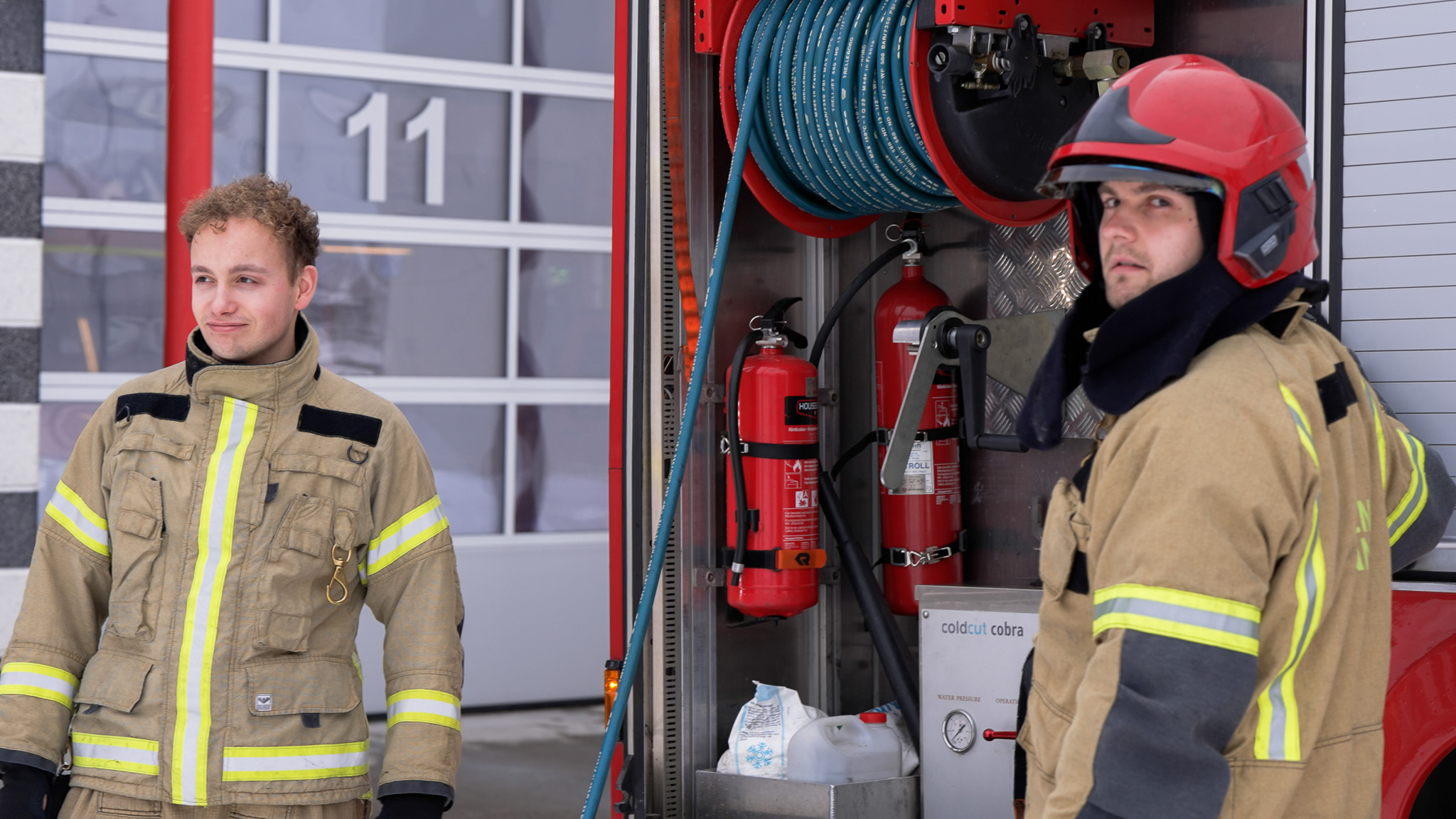 To mannlige brannkonstabler står ved brannbilen