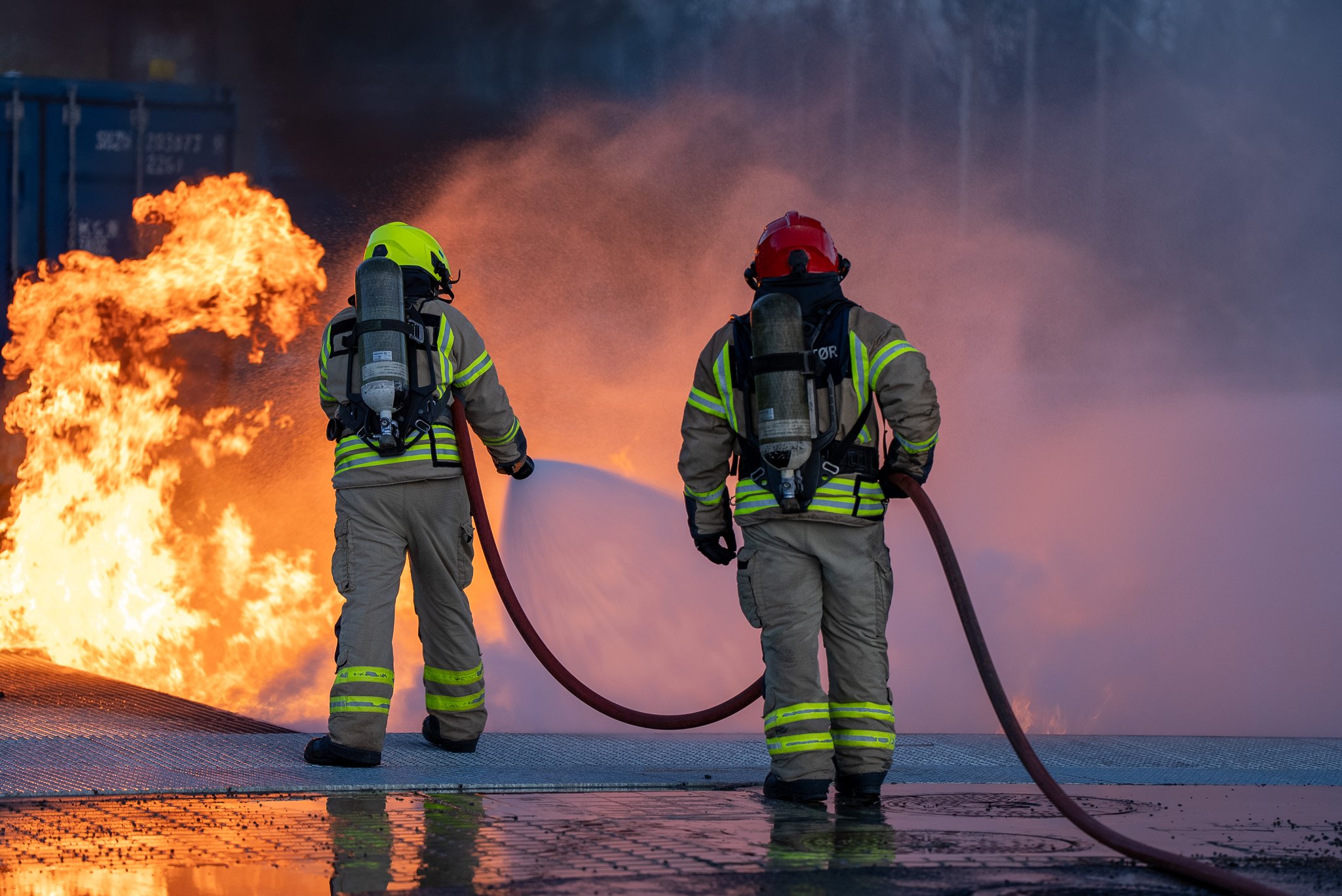 To brannkonstabler med ryggen til slokker en brann