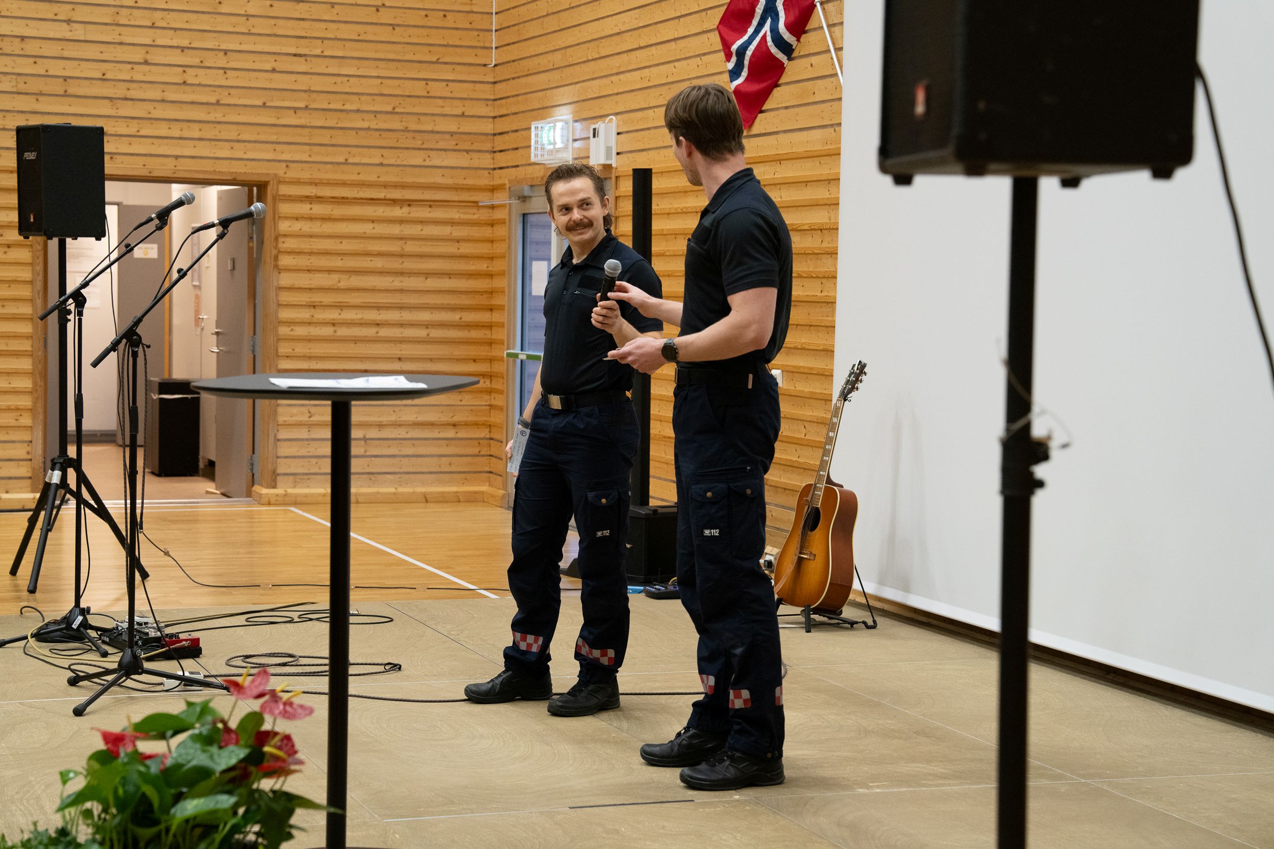 To menn i uniform står på en scene. Godt humør