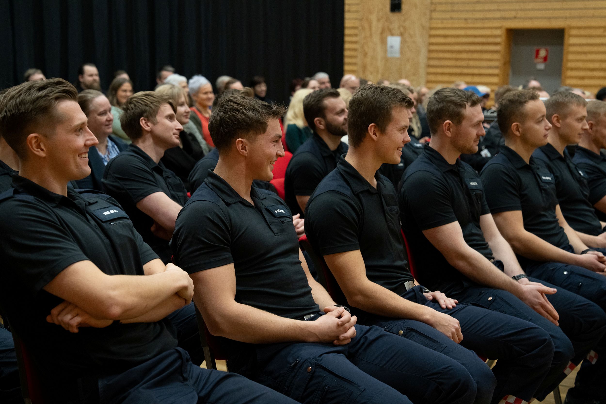 En gruppe menn i uniform sitter i publikum og følger med på noe som skjer foran dem