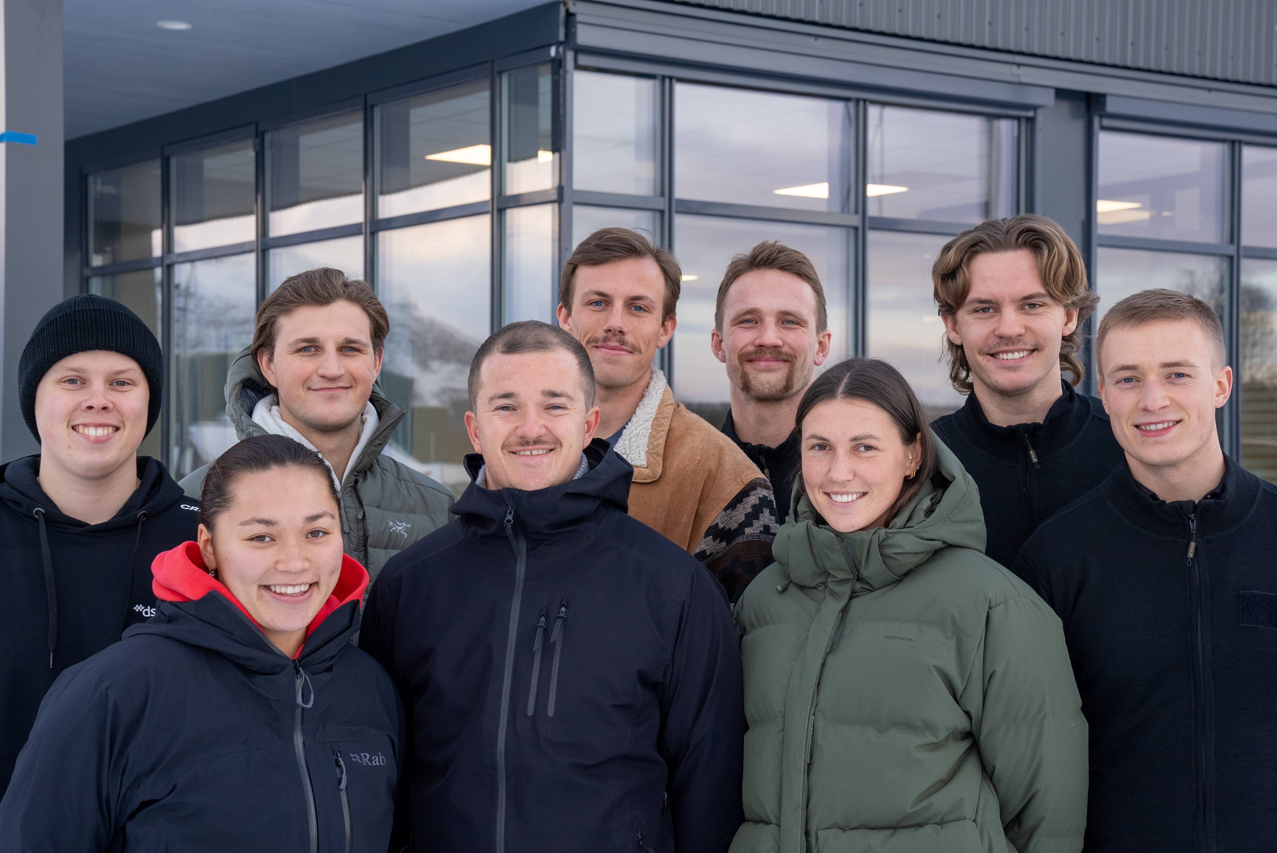 Ni blide studenter ser rett inn i kamera.