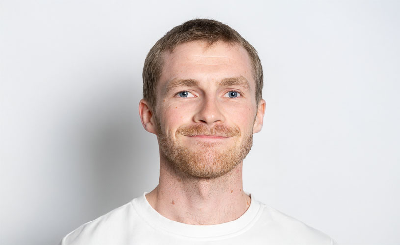 Ung mann ser vennlig inn i kameraet. Portrettbilde