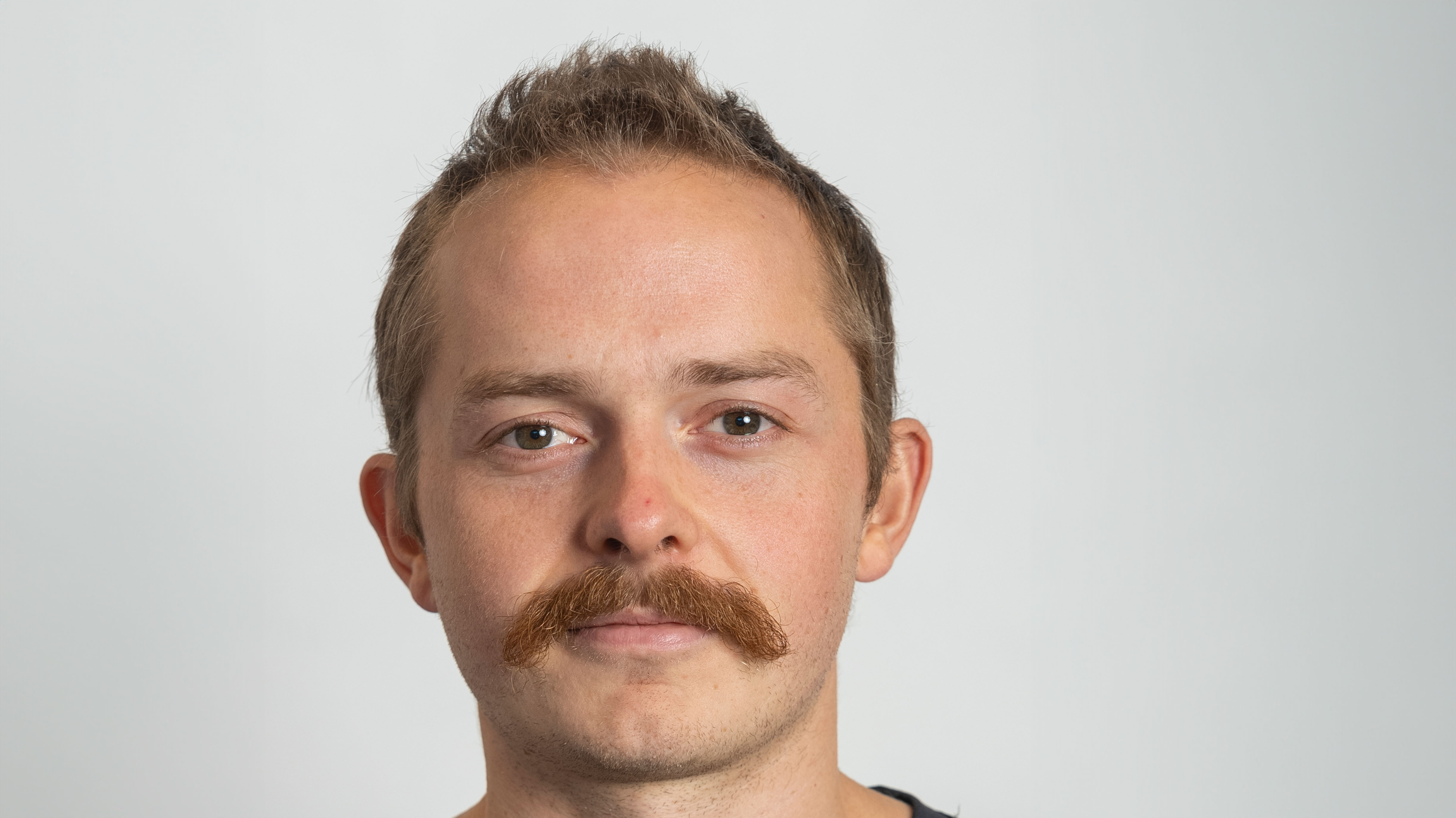 Portrettbilde av ung mann med stor bart. Foto