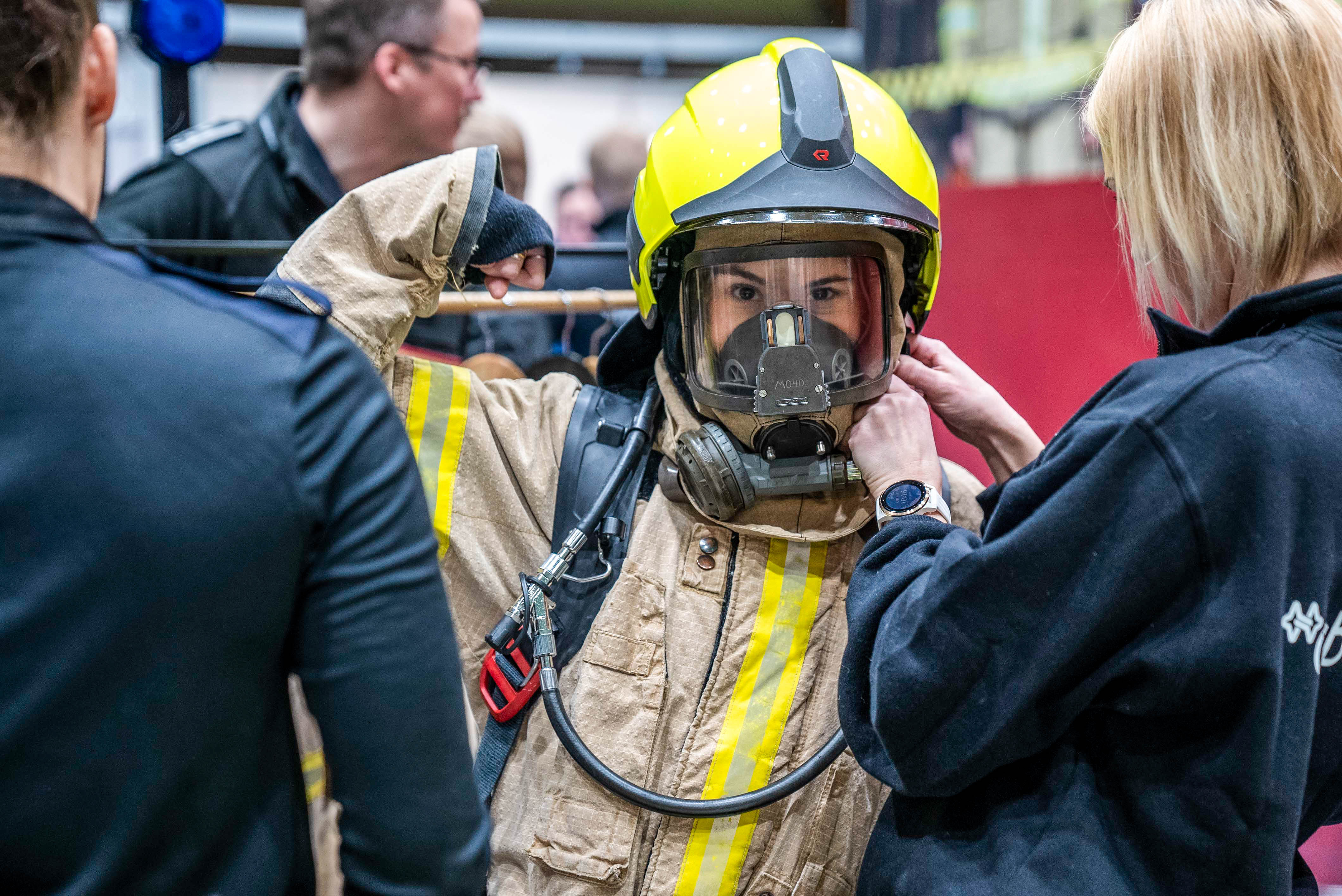 Elev har på røykdykkerbekledning og ser i kamera mens hun poserer